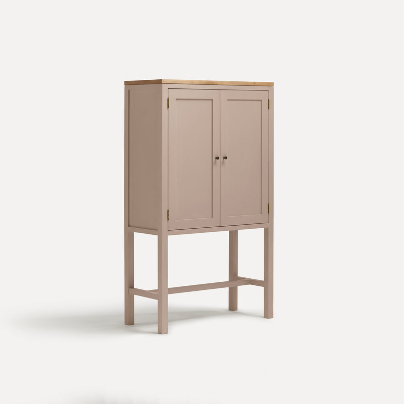 Pink painted two door shaker style cabinet on tall legs with oak work top.  Shown at angle.